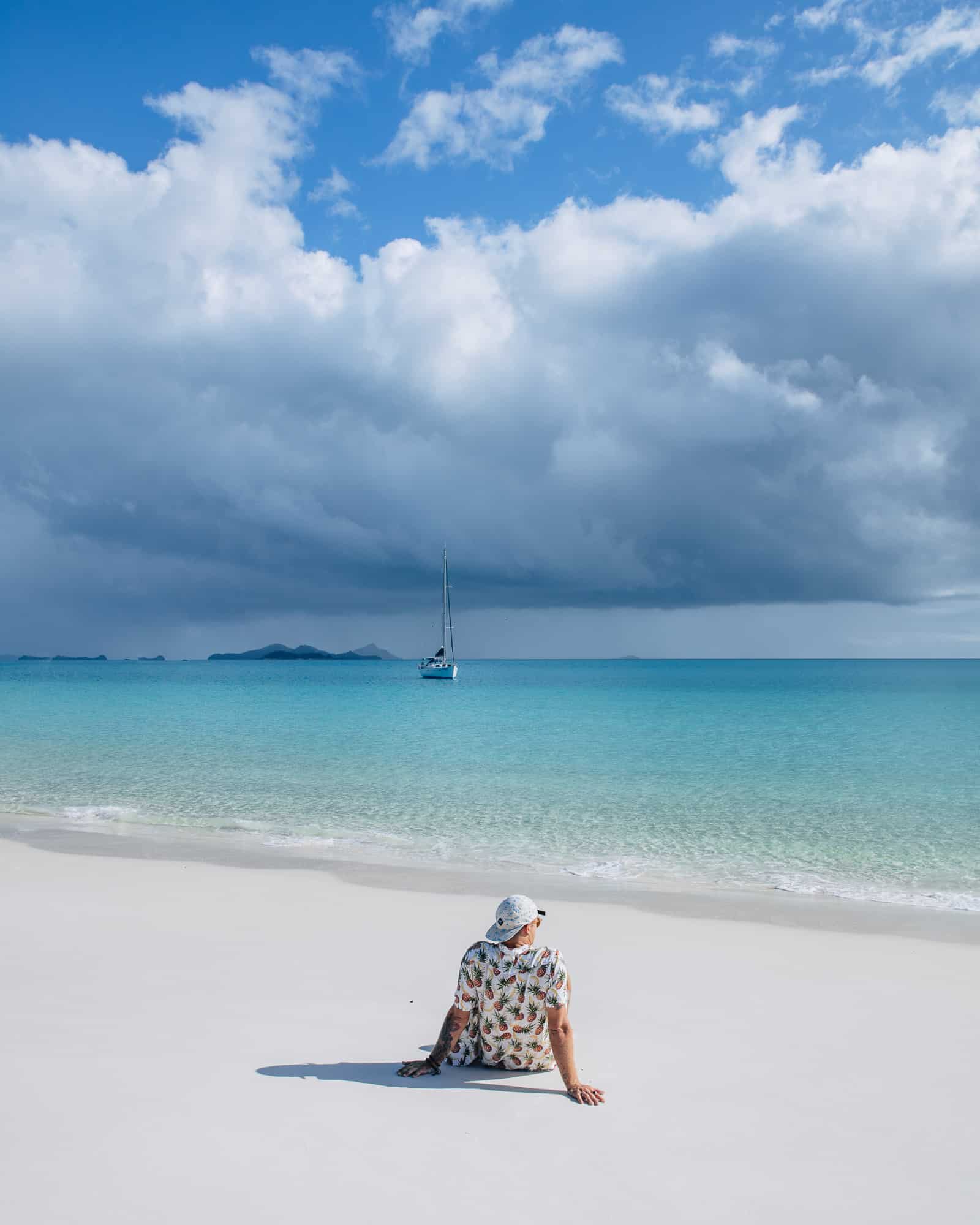 Man sitting on the beach on the Whitsundays on a beautiful day on Hamilton Island